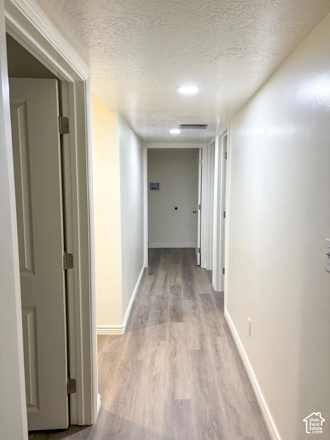 Hallway featuring wood-finish flooring, recessed lighting, and white trim