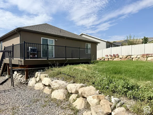 Rear exterior featuring a stucco finish, a deck with black metal railings, and a sliding glass door