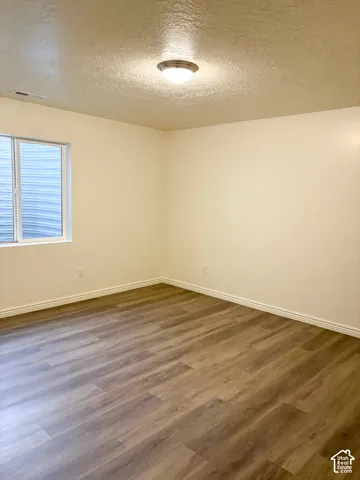 Wood-finish flooring with white baseboards and painted walls