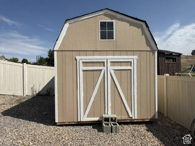 Gambrel-style shed with double doors and an upper window, set on a gravel base