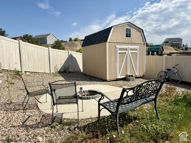 Private fenced backyard with a shed, concrete patio, and a built-in fire pit