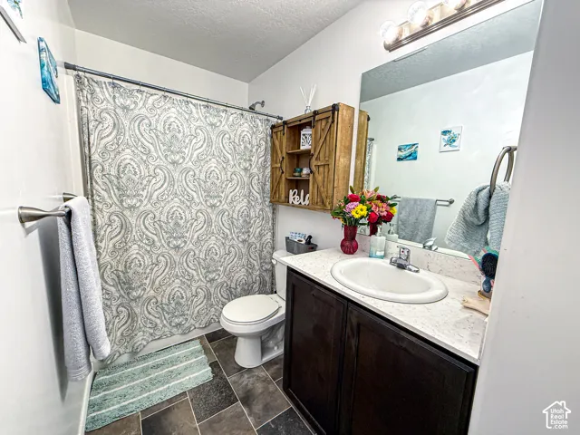 Bathroom featuring a built-in vanity with an integrated sink, dark wood-finish cabinetry, a large wall-mounted mirror, and tile flooring