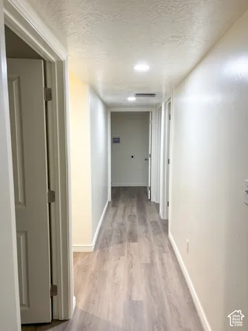 Hallway featuring wood-finish flooring, recessed lighting, and white trim