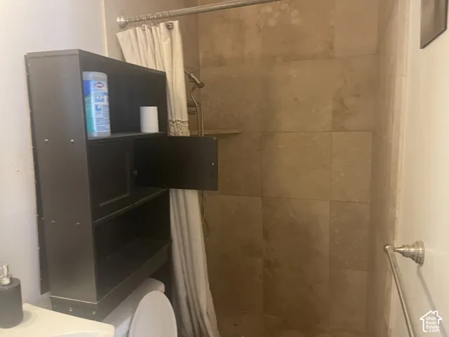 Shower with stone tile surround, integrated shower shelf, and a curved shower rod