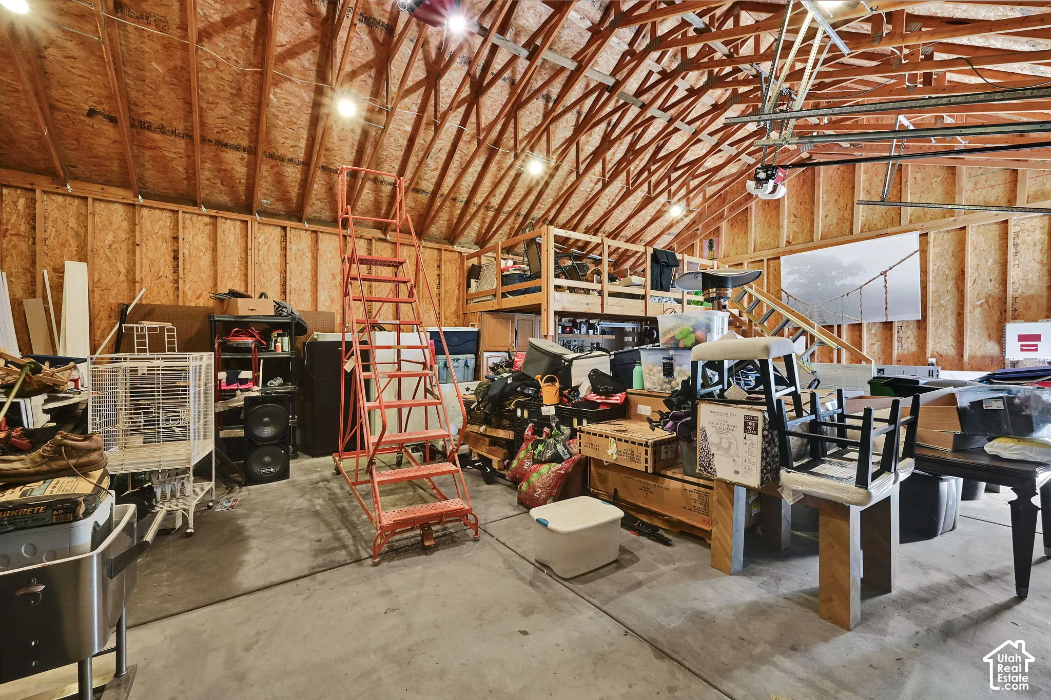 Exposed wood beam ceiling with lighting, wood-paneled walls, and concrete flooring