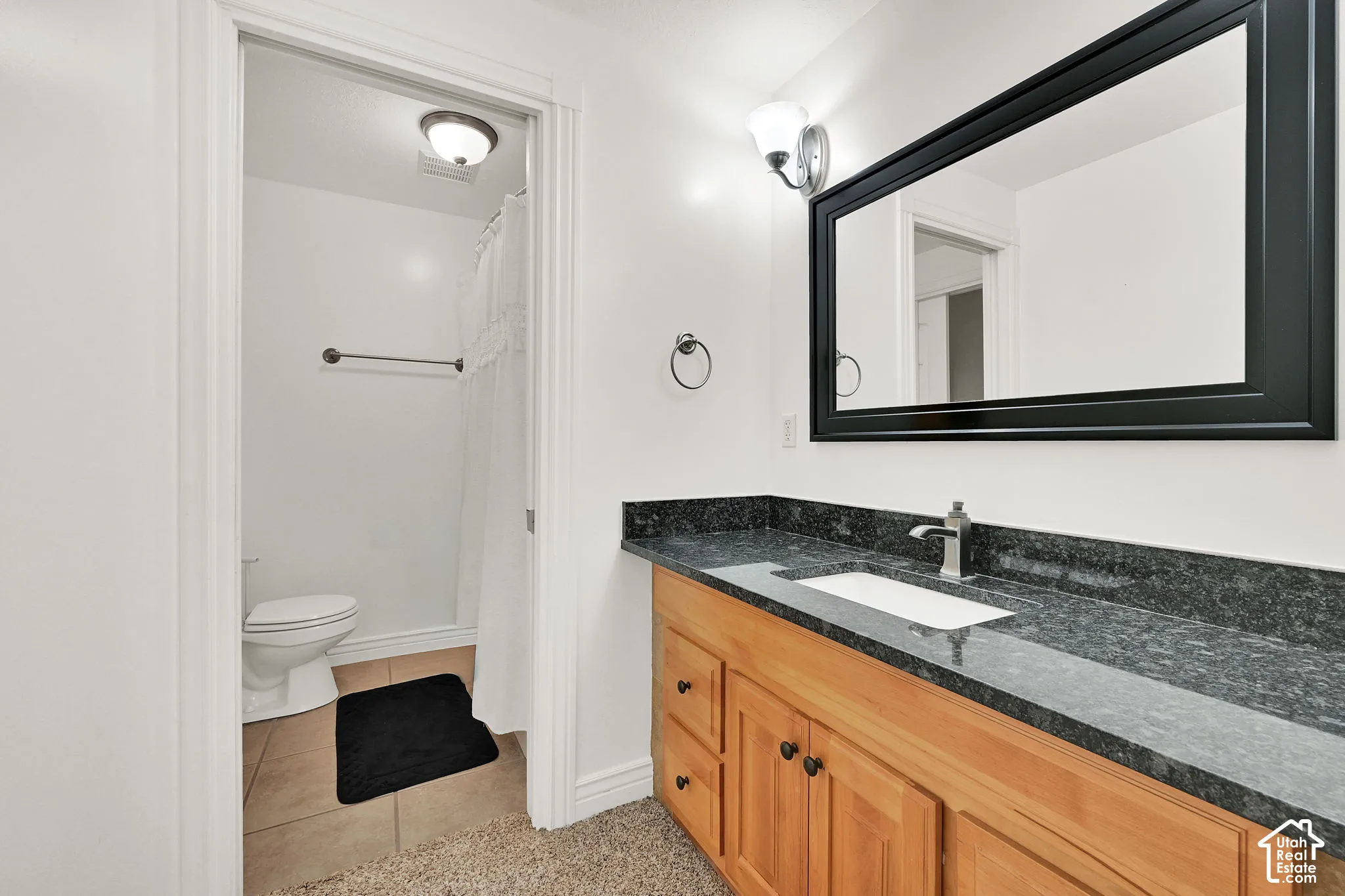 Wood-finish vanity with an integrated sink, dark speckled countertop, and a wall-mounted mirror