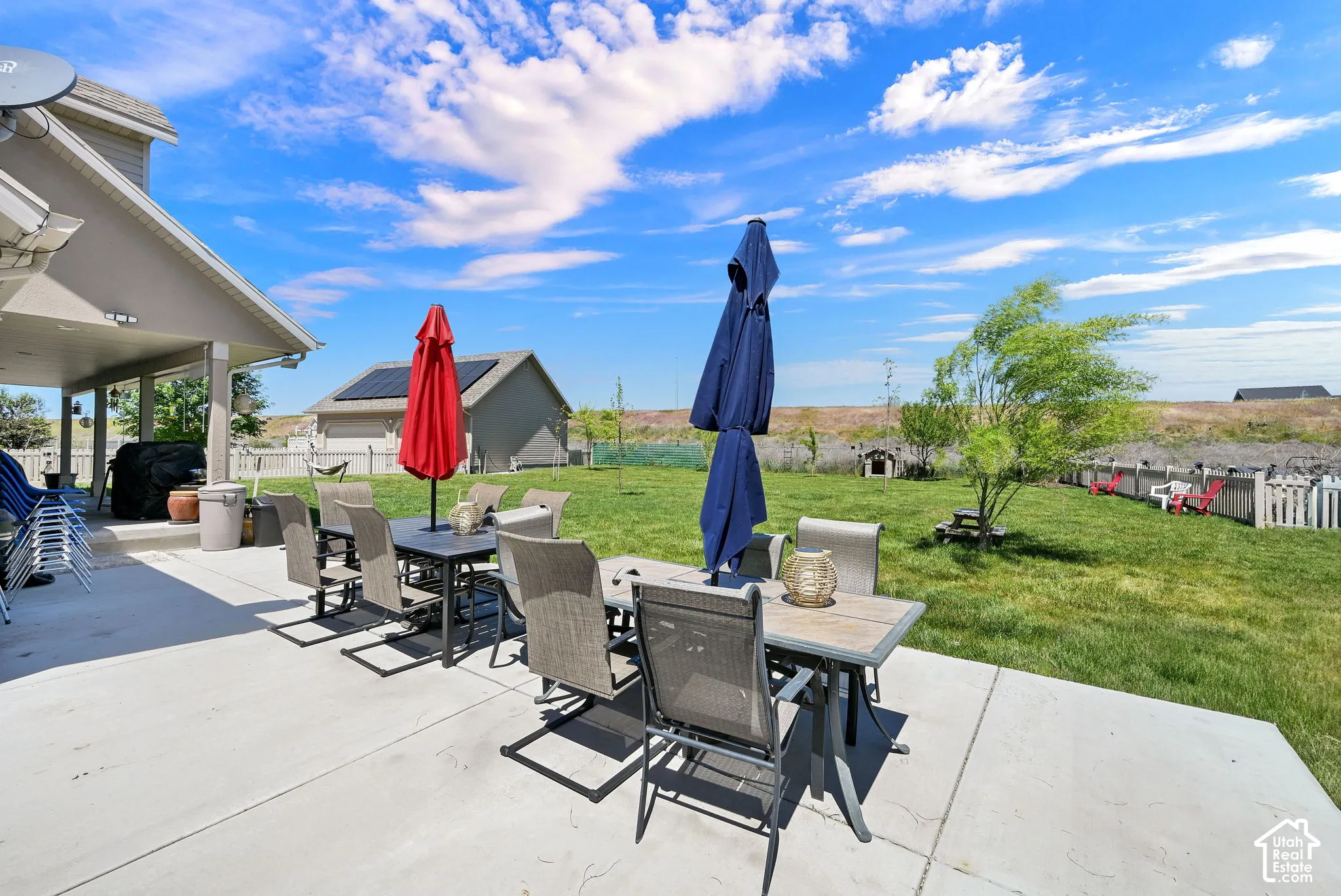 Expansive concrete patio with a covered outdoor living area and a large grassy yard