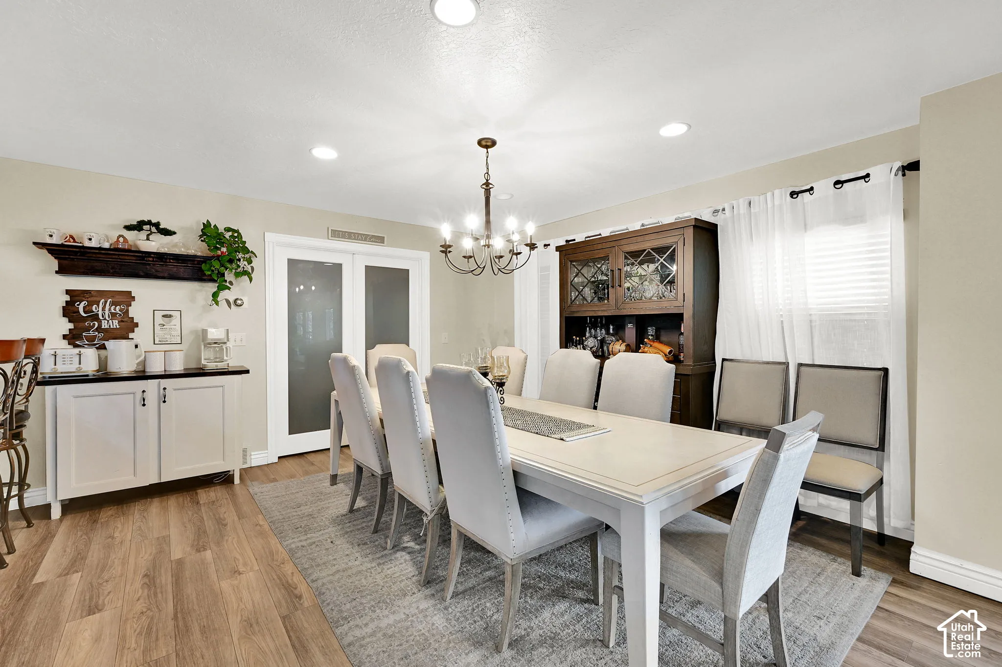 Recessed lighting, wood-finish flooring, chandelier, white painted cabinetry, and double glass-paneled doors