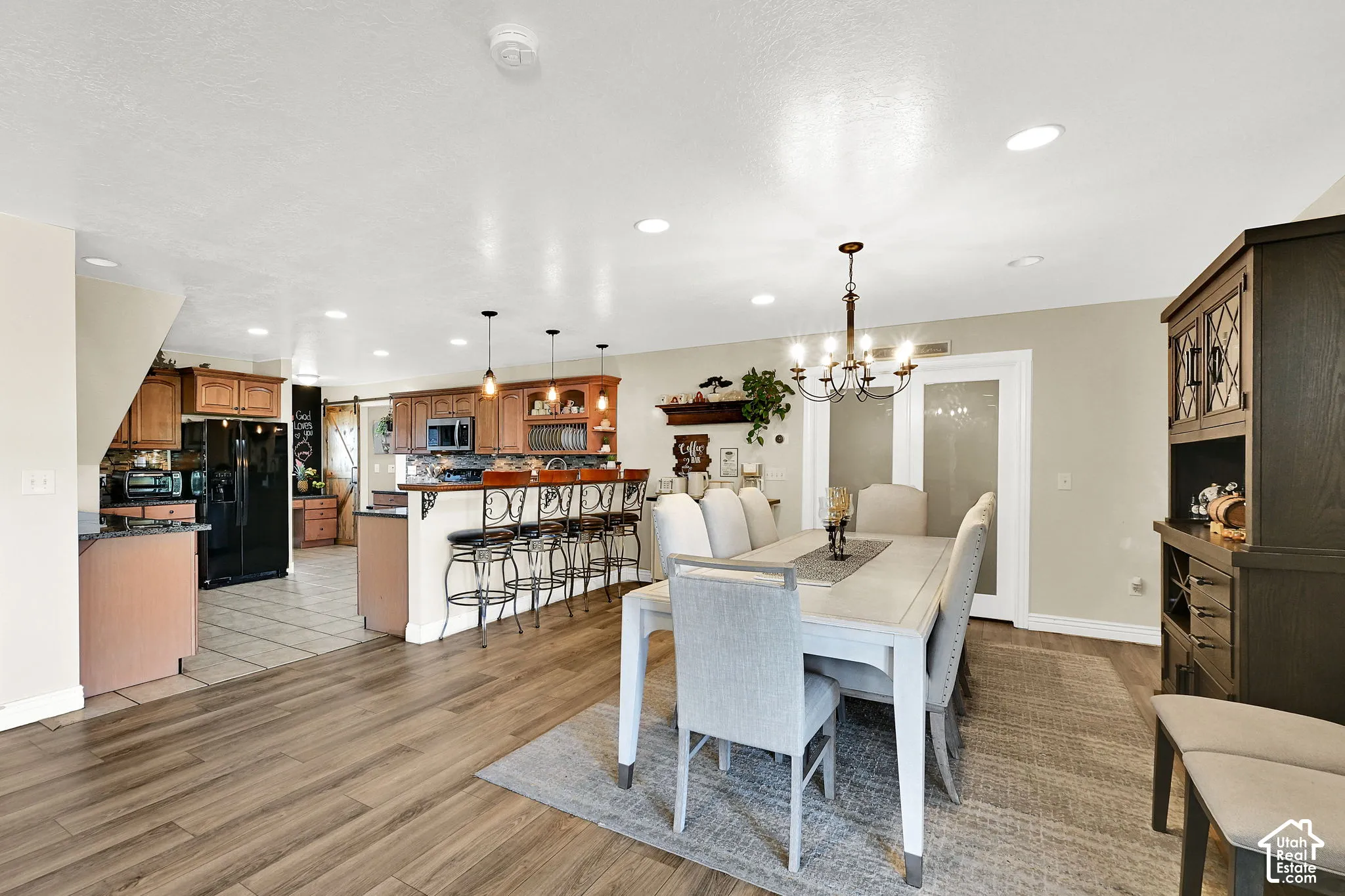Open-concept dining area with wood-finish flooring, a multi-light chandelier, and recessed lighting