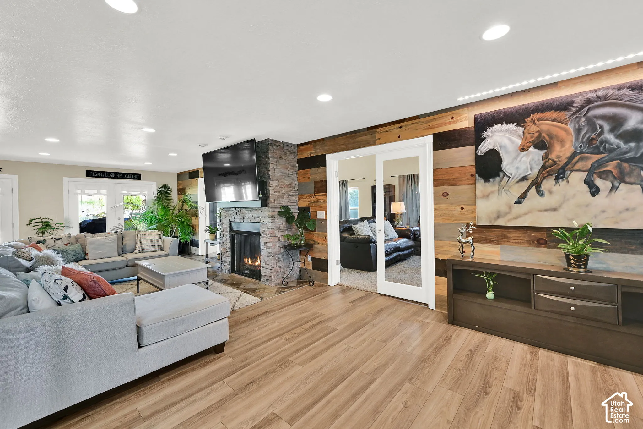 Spacious living area featuring wood-finish flooring, a stone-clad fireplace, and recessed lighting