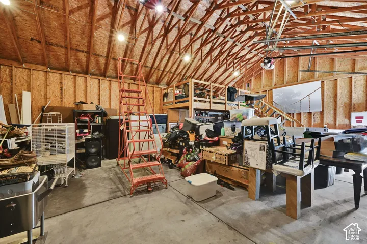 Exposed wood beam ceiling with lighting, wood-paneled walls, and concrete flooring
