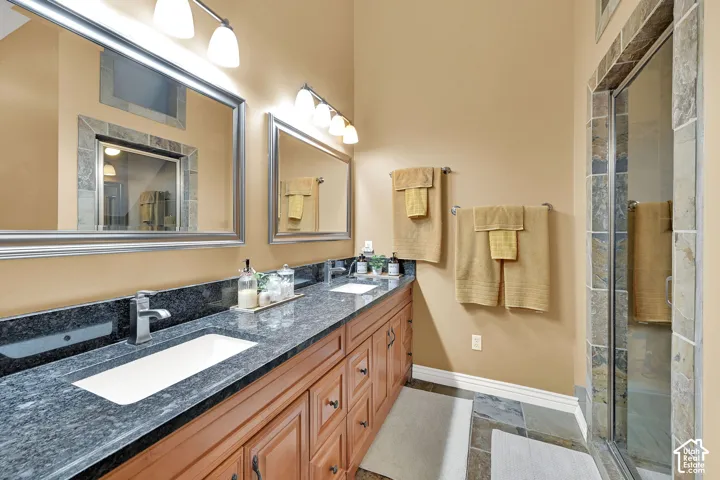 Dual vanity with granite countertop, integrated sinks, and wood cabinetry