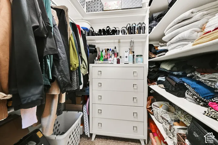Built-in closet system featuring white shelving, hanging rods, and a central dresser with five drawers
