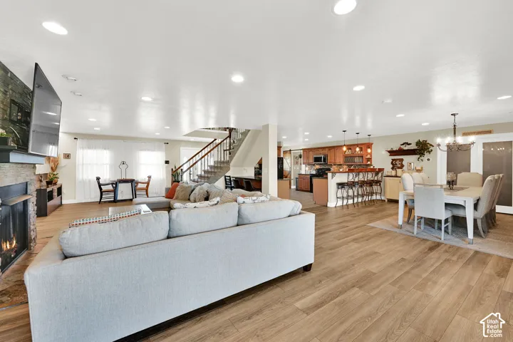 Open-concept living space featuring a light gray upholstered sectional sofa, wood-finish flooring throughout, recessed ceiling lighting, and a staircase with black metal railings