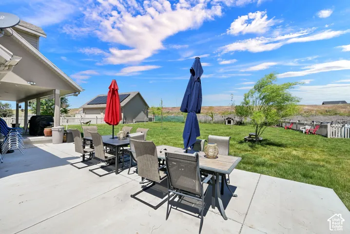 Expansive concrete patio with a covered outdoor living area and a large grassy yard