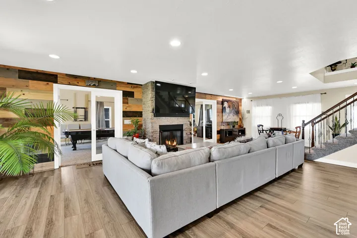 Wood-finish flooring, recessed lighting, and a stone-clad fireplace with a hearth