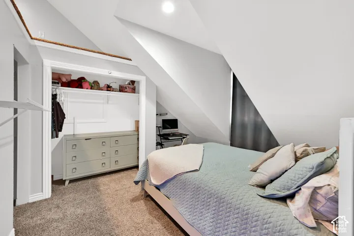 Carpeted flooring with sloped ceilings, recessed lighting, and a built-in closet with shelving