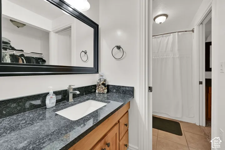 Vanity with a dark patterned countertop, integrated rectangular sink, brushed nickel faucet, and wood-finish cabinetry