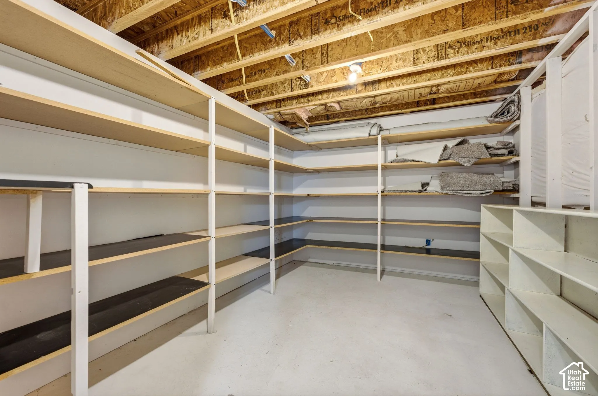 Extensive built-in shelving, exposed wood ceiling joists, and concrete flooring