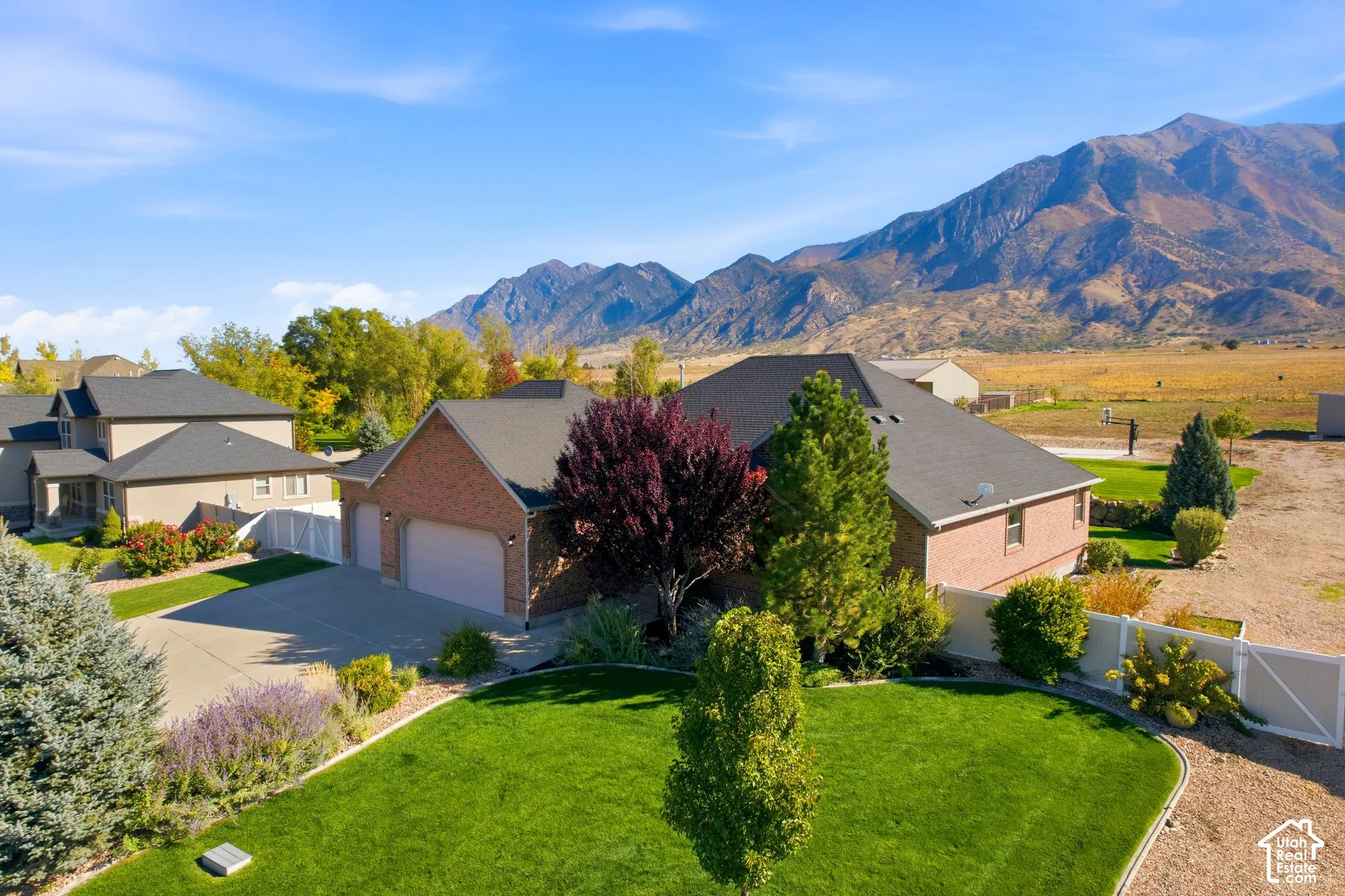 Brick exterior with a multi-car garage, mature landscaping, and a mountain backdrop