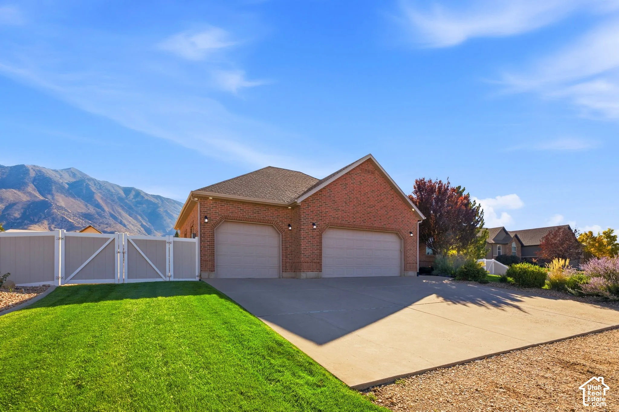 Brick exterior featuring a two-car garage with arched entrances, a paved driveway, and a manicured lawn