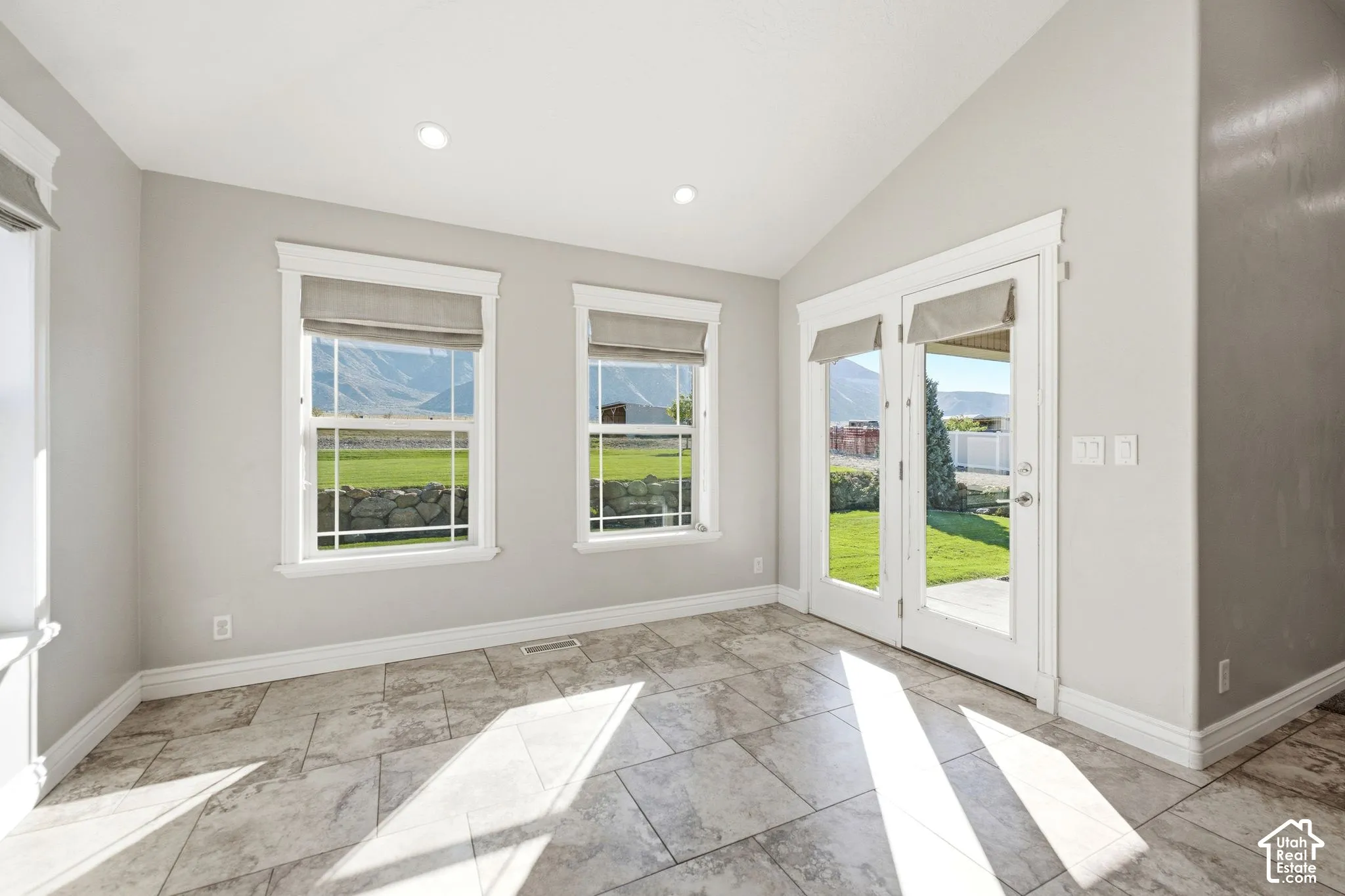 Vaulted ceiling with recessed lighting, tile flooring, and French doors leading to exterior