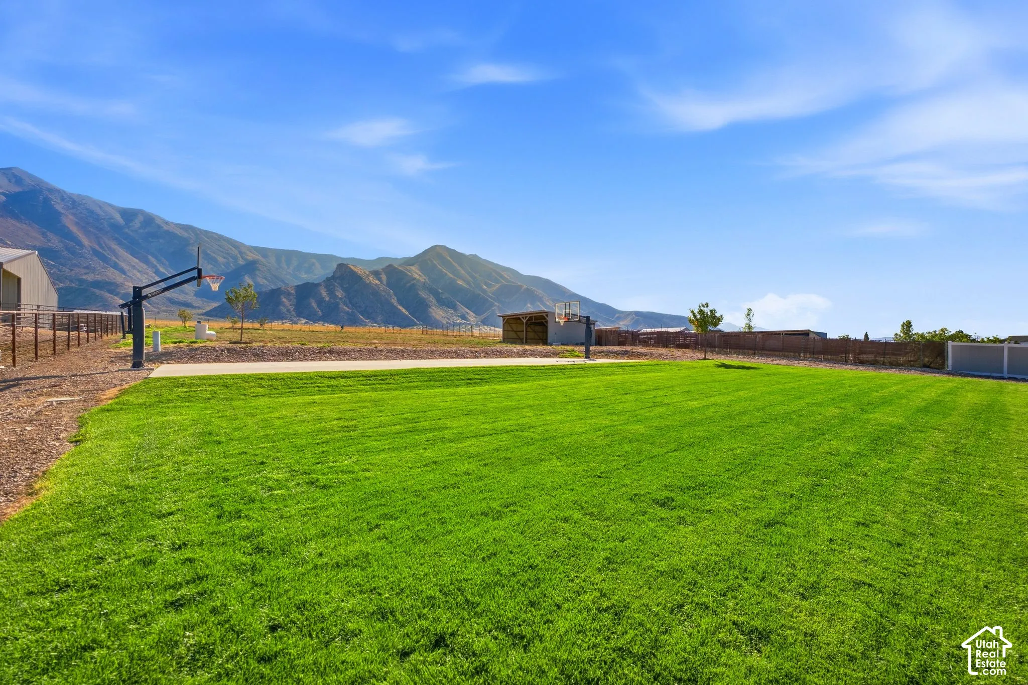 Expansive lawn area with a paved court, basketball hoop, and distant mountain scenery