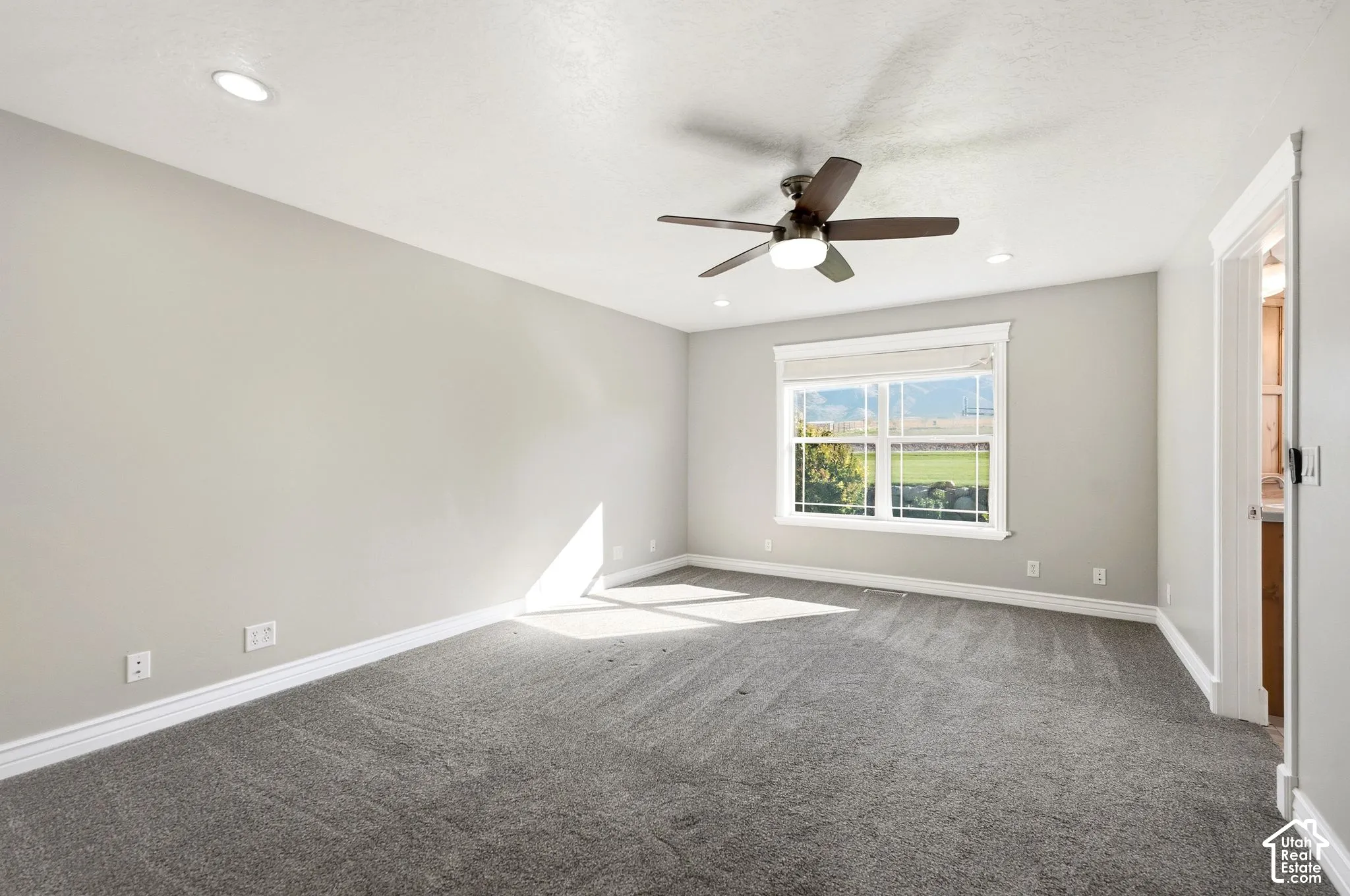 Recessed lighting, ceiling fan with integrated light, carpeted flooring, and a large window with white trim