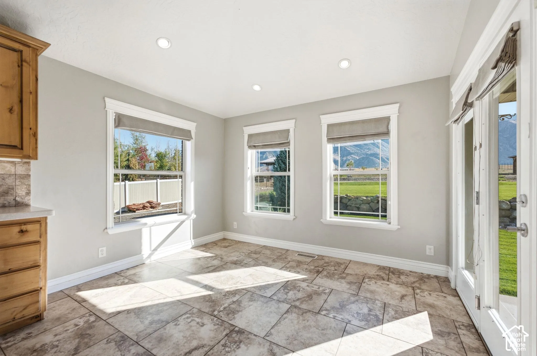 Tiled flooring, multiple windows, recessed lighting, wood cabinetry, and a glass-paneled door
