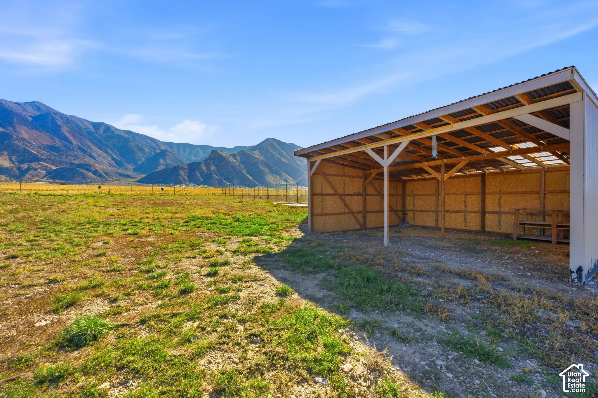 Open-sided structure featuring exposed wood framing, a corrugated roof, and translucent roof panels