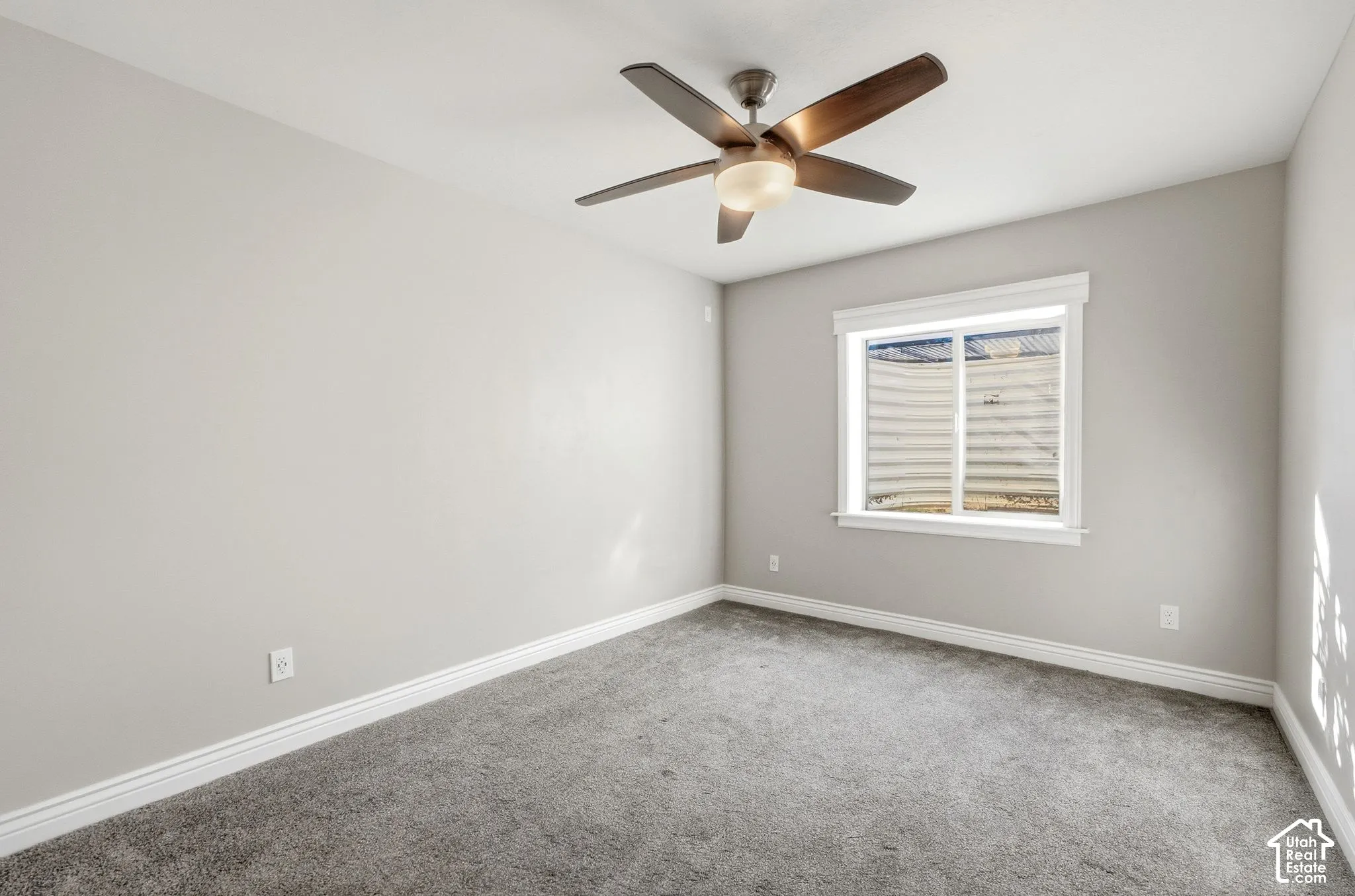 Wall-to-wall carpeting, ceiling fan with integrated lighting, and a window with white trim