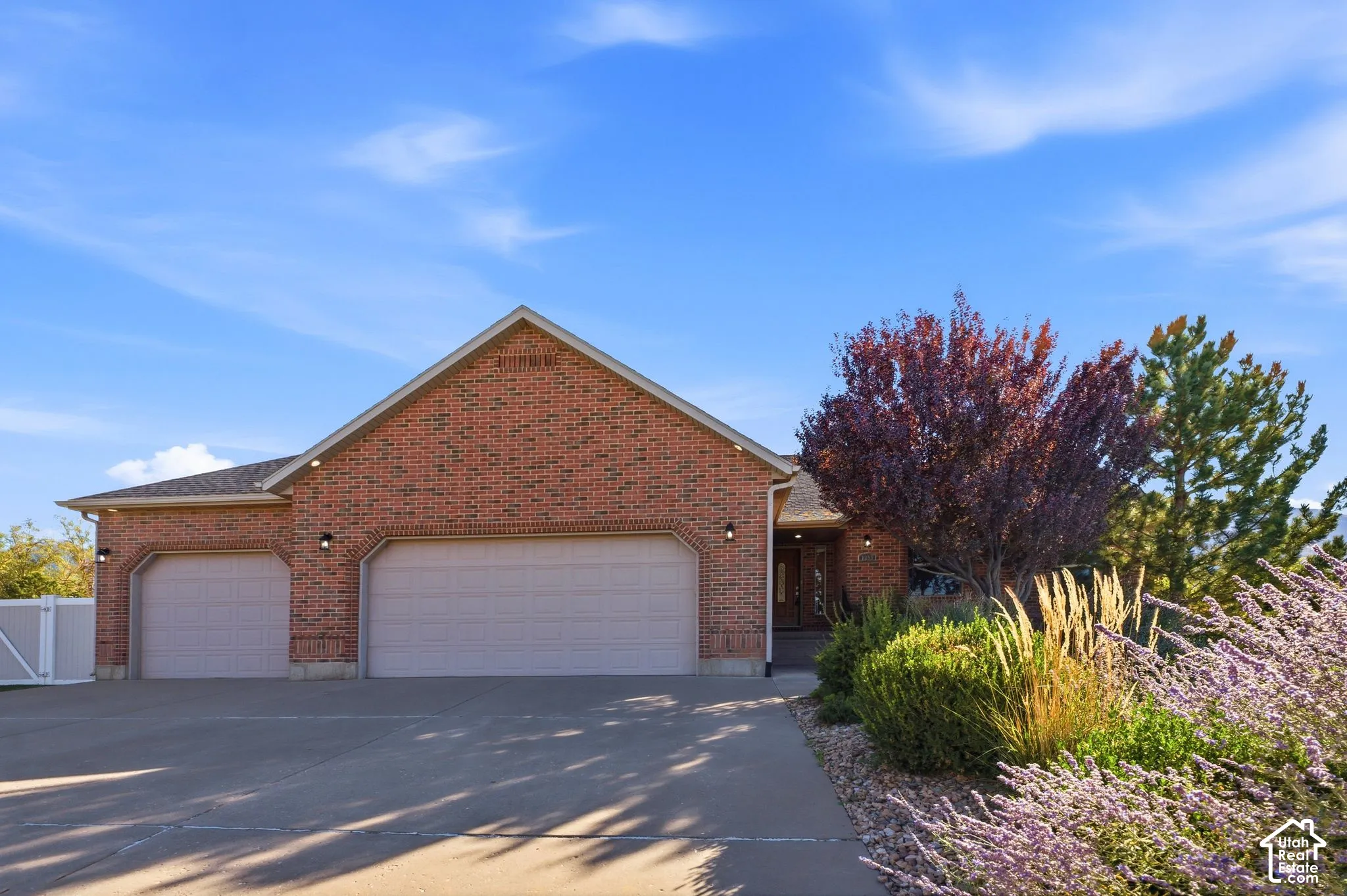 Brick exterior with a gabled roofline, multiple garage bays, and a covered entryway
