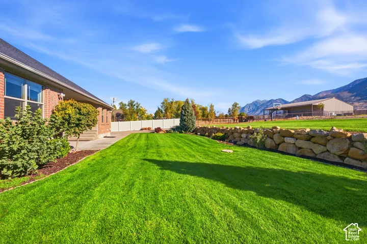 Expansive lawn area with a stone retaining wall and mature landscaping
