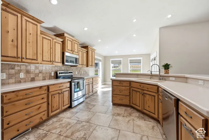 Kitchen featuring wood cabinetry, stainless steel appliances, light-toned countertops, and tile flooring