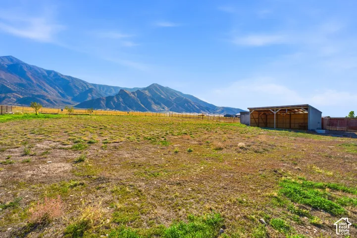 Expansive open field with a permanent shed structure and mountain backdrop