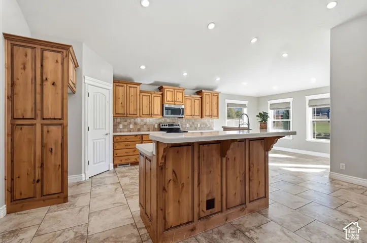 Kitchen featuring a central island with countertop seating, wood cabinetry, tile flooring, and recessed lighting