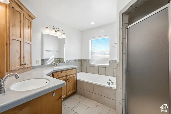 Dual vanity with wood cabinetry, a built-in tub, separate shower, and tiled flooring
