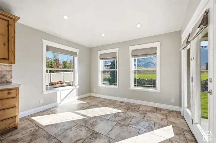 Tiled flooring, multiple windows, recessed lighting, wood cabinetry, and a glass-paneled door