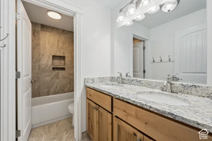 Double vanity with granite countertop, integrated sinks, wood cabinetry, and brushed nickel fixtures