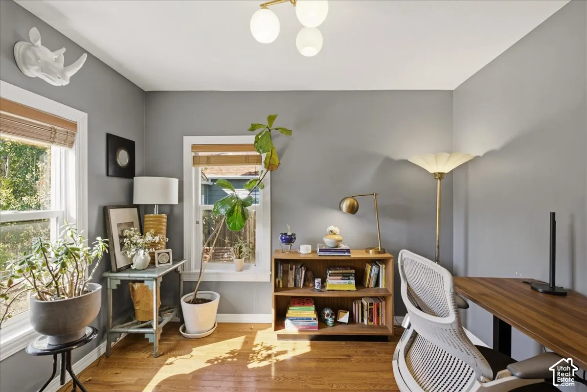 Hardwood flooring, painted walls, two windows with blinds, and a built-in bookshelf