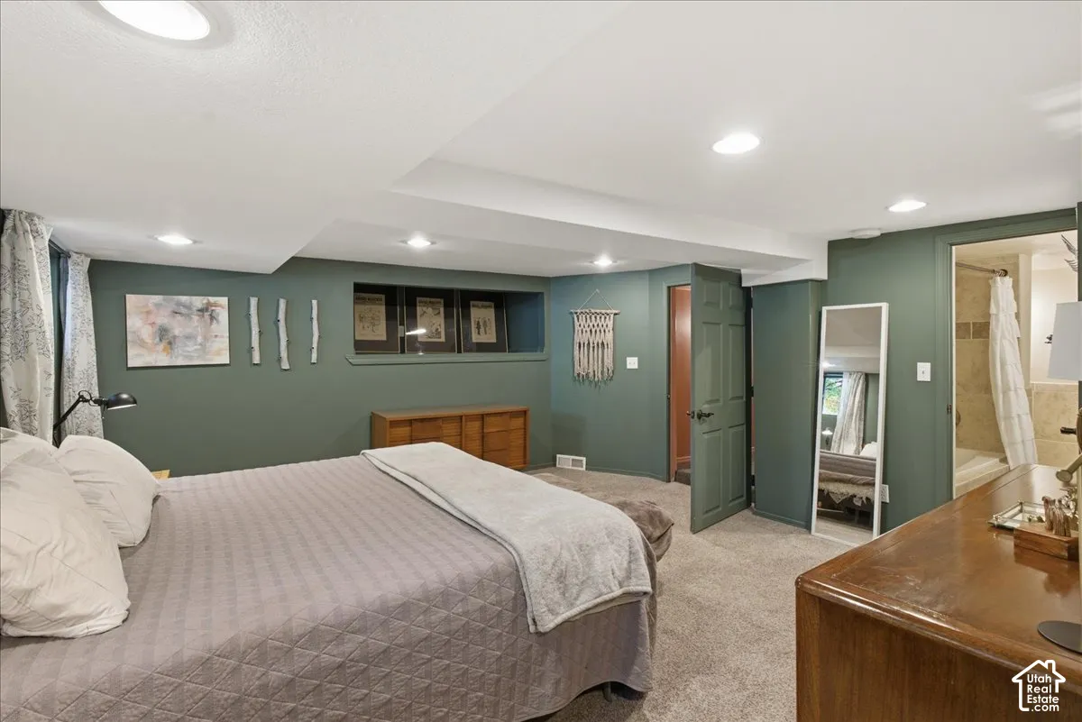 Recessed lighting, wood-finish interior doors, built-in shelving, carpet flooring, and an attached bathroom with tiled shower surround
