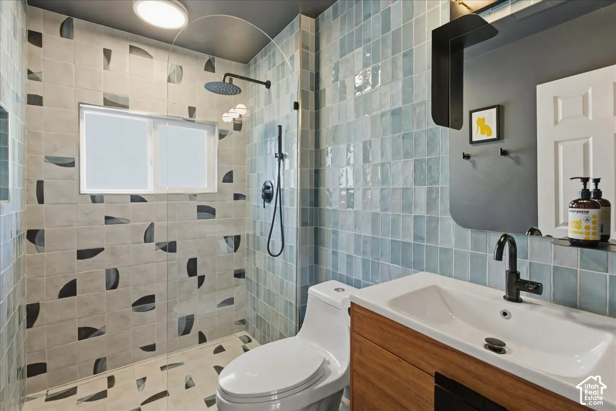 Walk-in shower with rain showerhead, mosaic tile surround, window, and integrated wood-finish vanity with basin sink