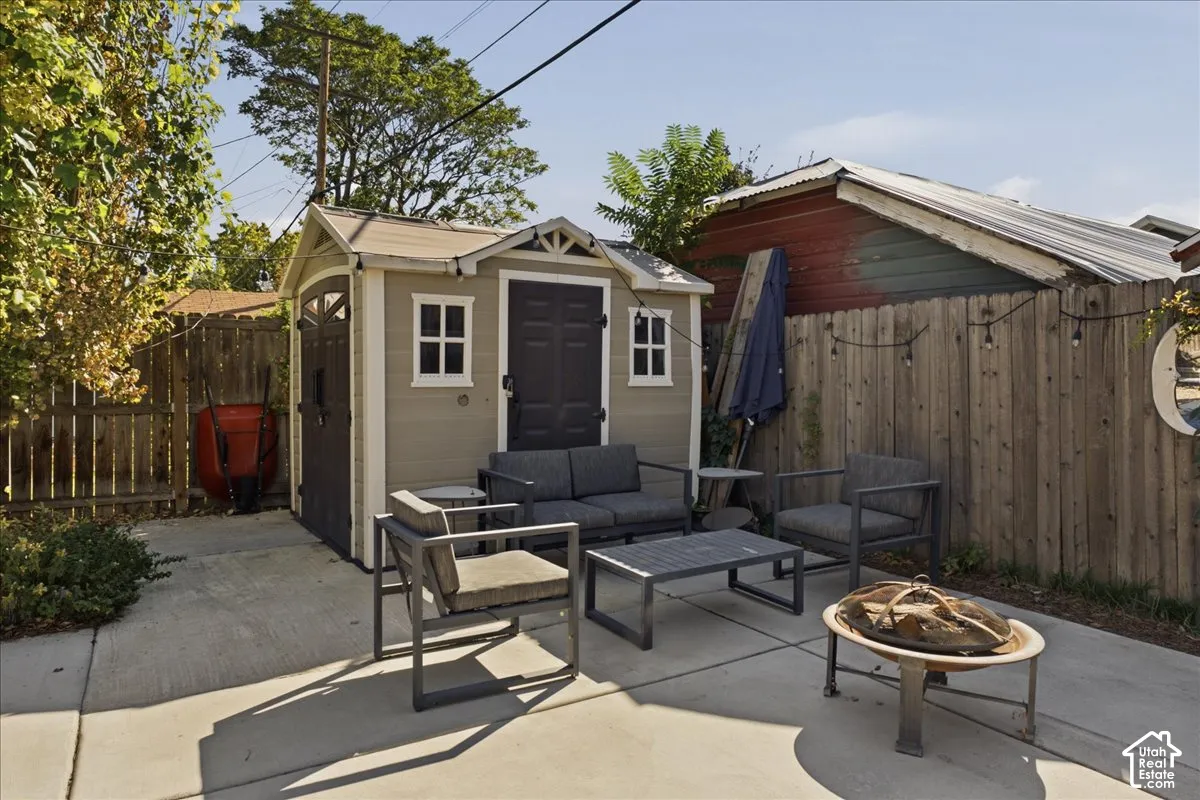 Concrete patio area with a detached shed, wood privacy fencing, and string lighting