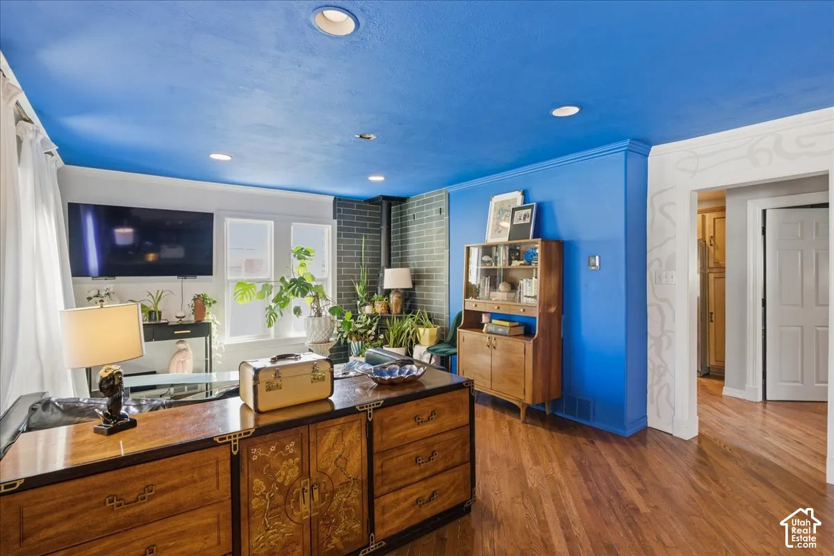 Recessed lighting illuminates the space, featuring wood-finish flooring and a brick accent wall