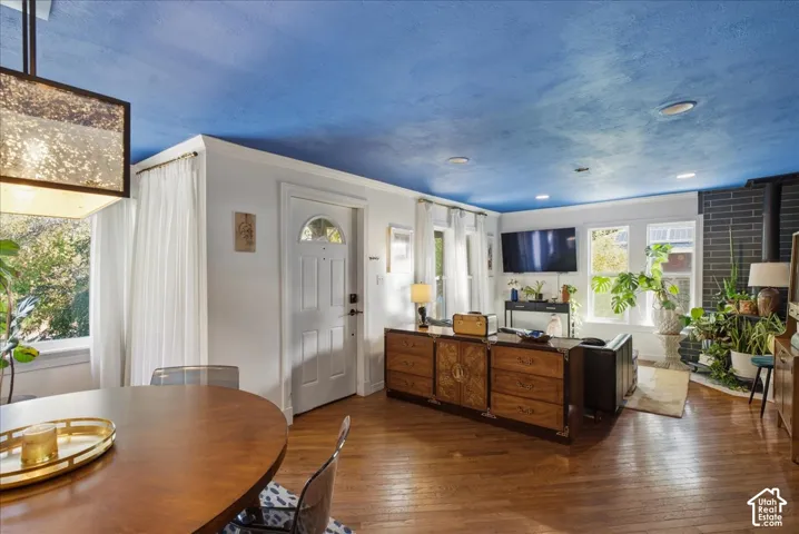 Hardwood flooring throughout, a front entry door with an arched window, a contemporary fireplace with a dark tile surround, and multiple large windows providing ample natural light