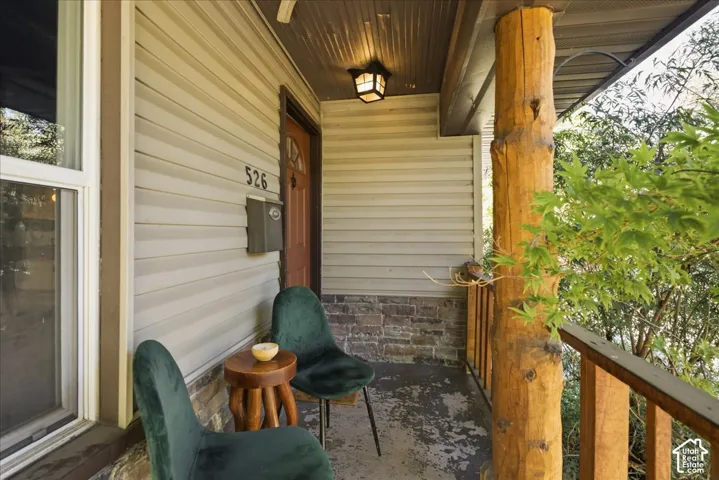 Front porch featuring natural wood pillars, a wood-finish entry door, and horizontal siding
