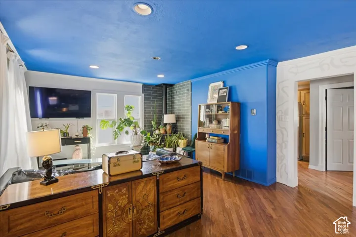 Recessed lighting illuminates the space, featuring wood-finish flooring and a brick accent wall