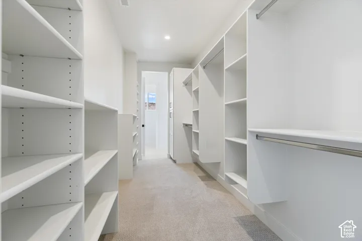 Expansive walk-in closet featuring built-in shelving, integrated hanging rods, recessed ceiling lighting, and carpet flooring