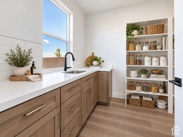 White countertops, wood-finish flooring, built-in shelving, full-height window, and matte black faucet
