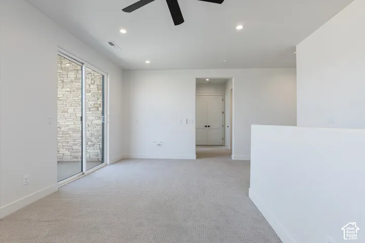 Sliding glass doors, recessed lighting, carpeted flooring, ceiling fan, and stone wall exterior
